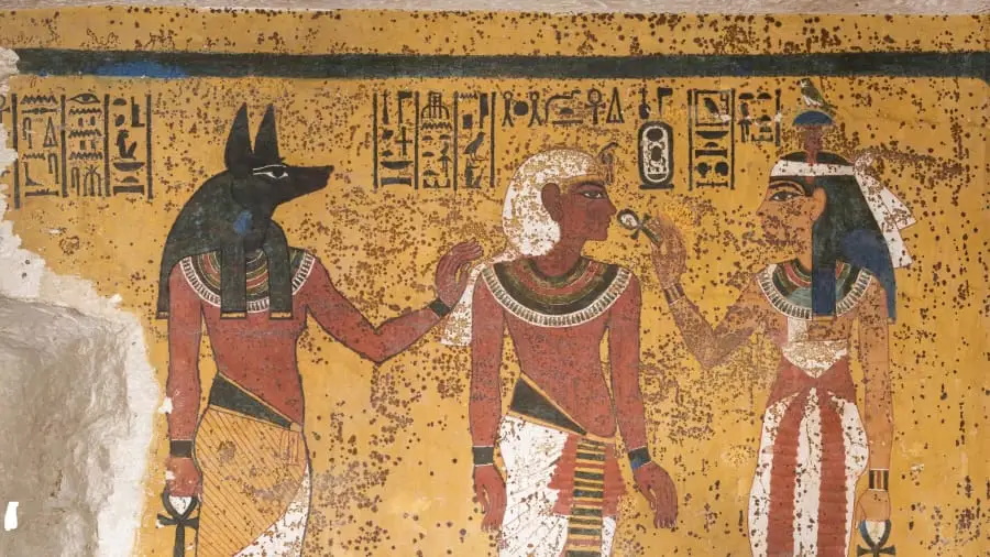 Fresco egipcio que representa al dios Anubis (izquierda), el difunto faraón Tutankamon en el centro y la diosa Hathor a la derecha